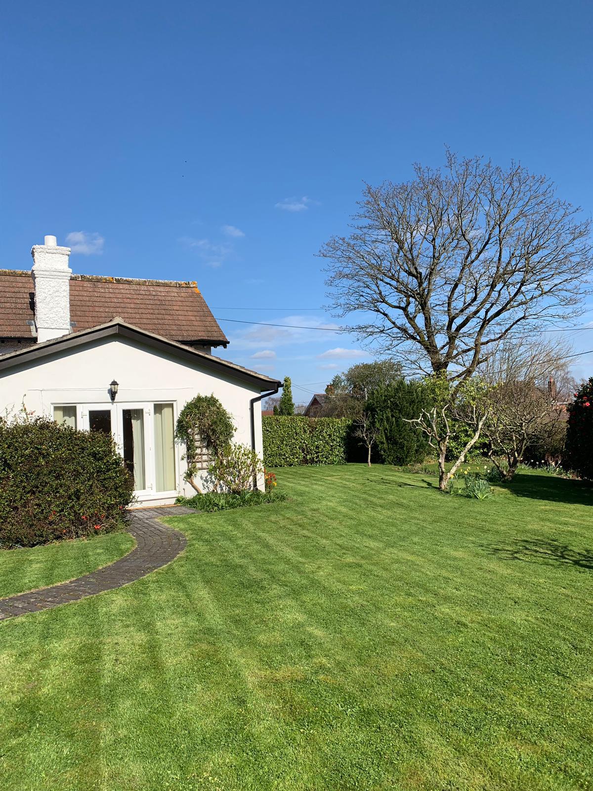 Striped lawn with cottage and hedges